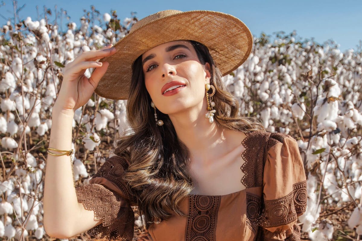 mulher de chapeu e look modesto no campo de algodao